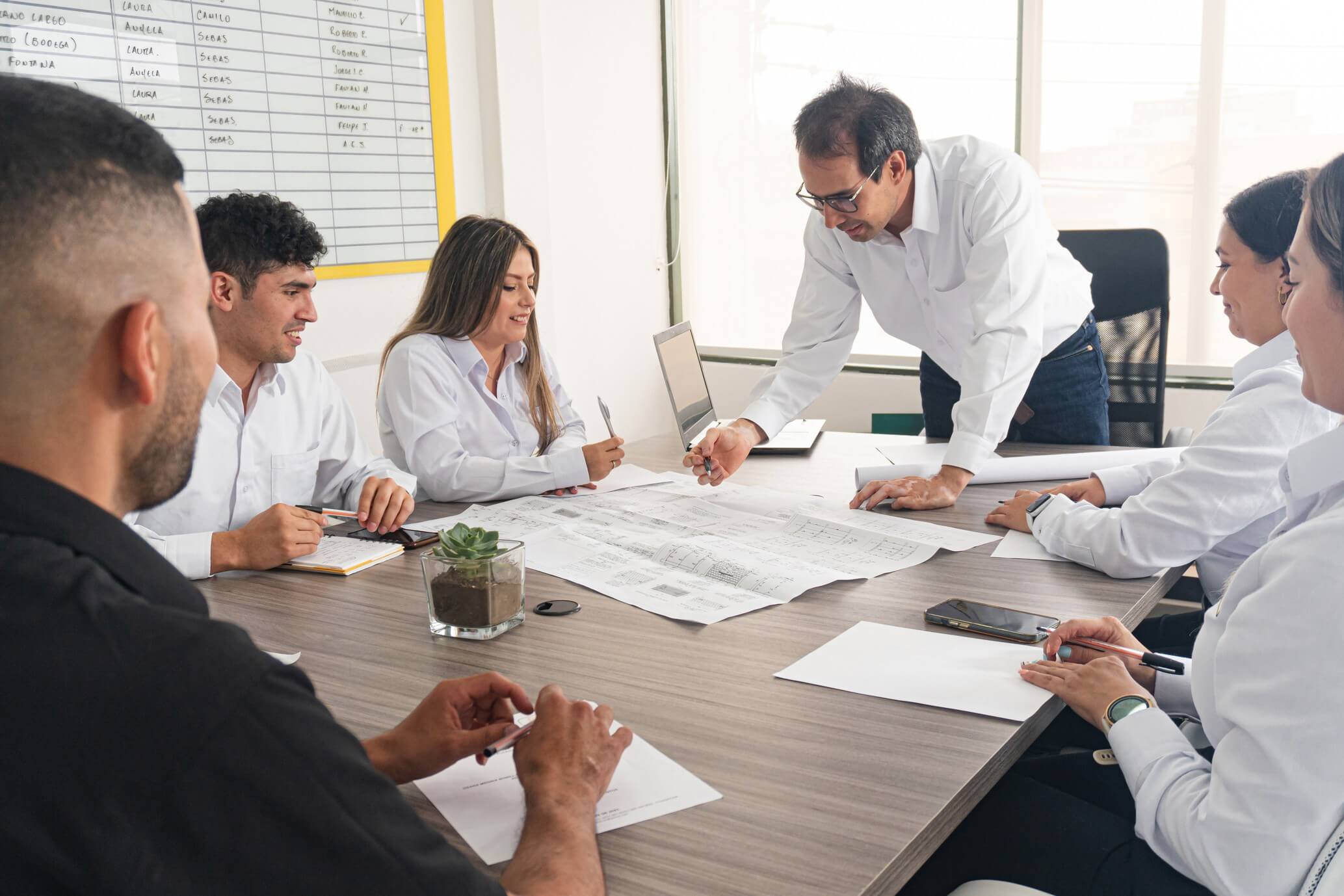 Team meeting with documents on table.