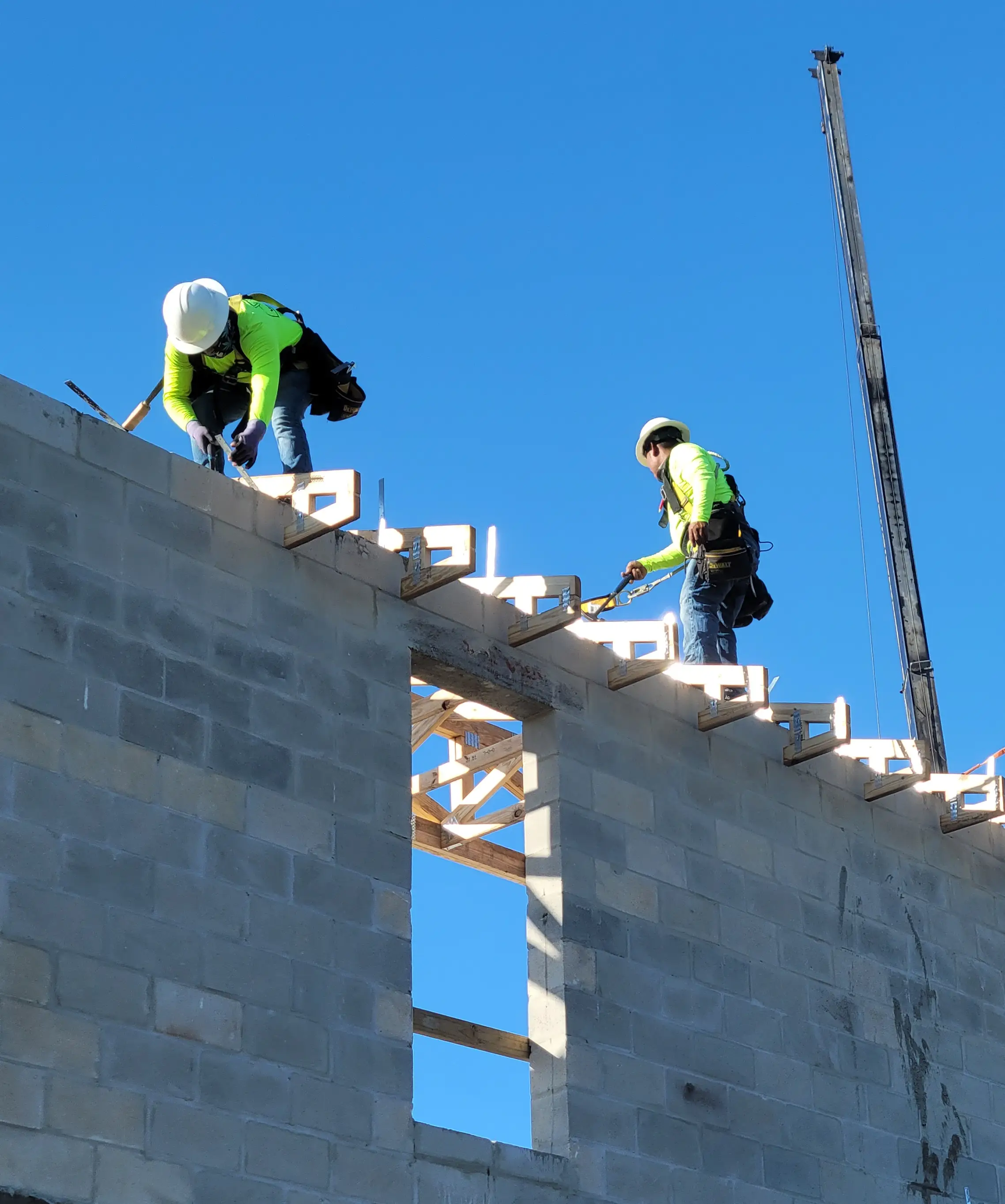 Construction workers building a concrete block wall.