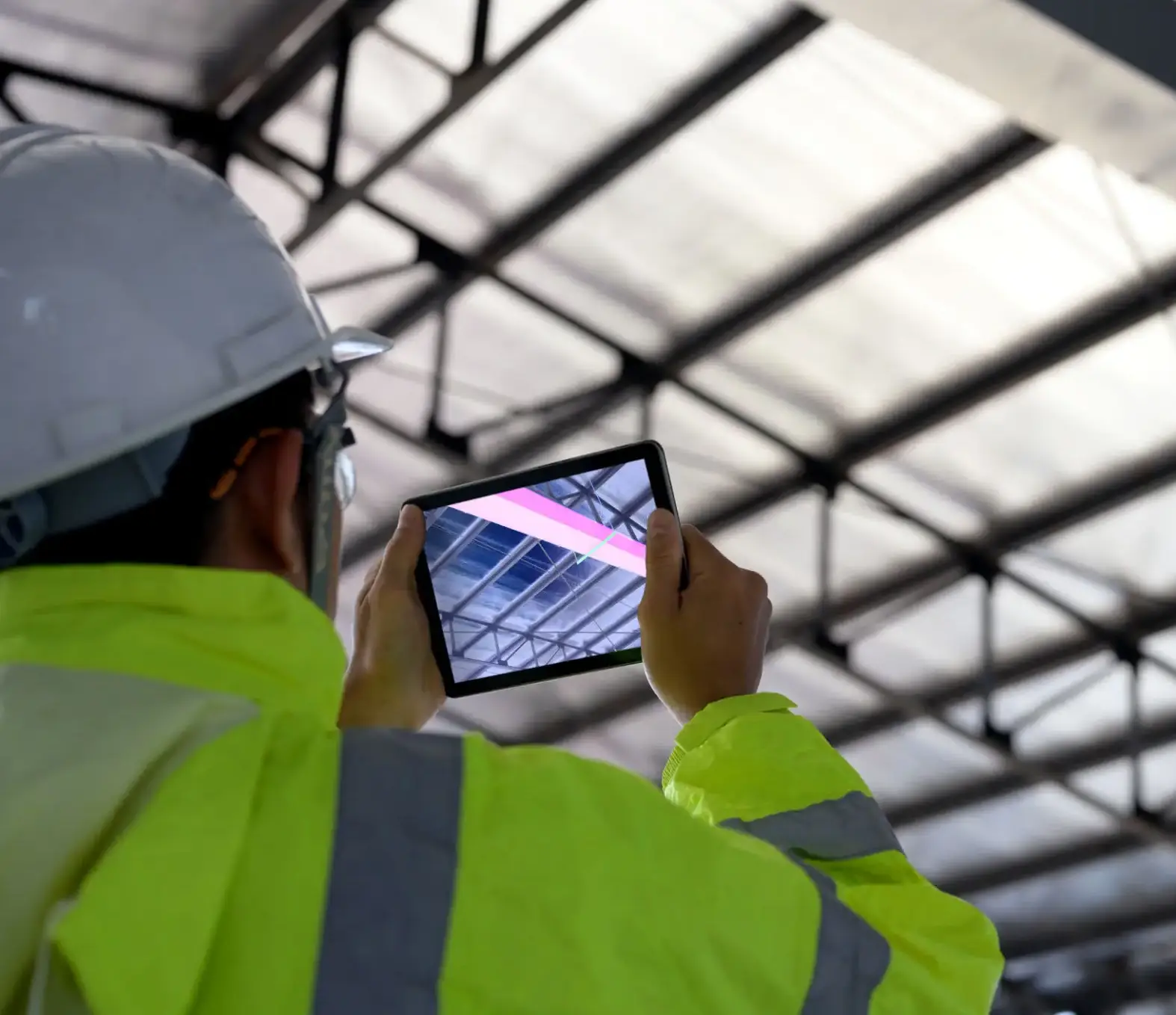 Worker in a safety vest using a tablet to inspect a roof.
