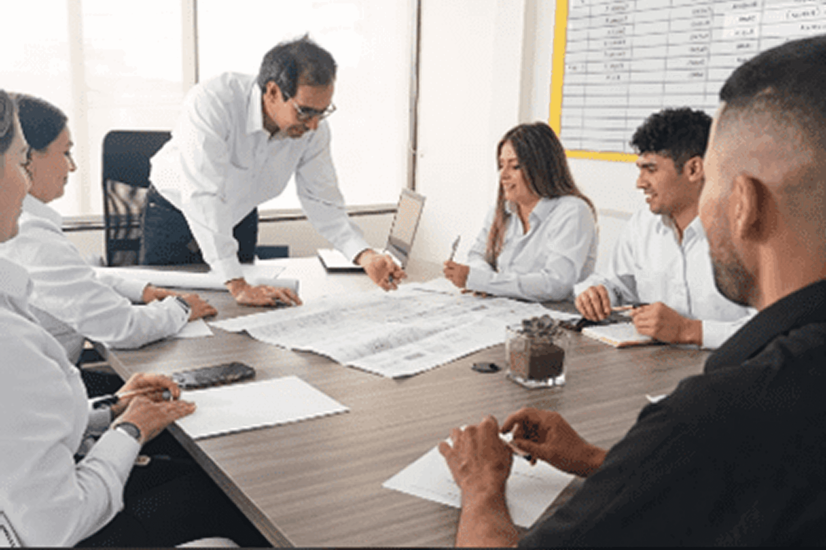 Team collaborating over architectural blueprints in a meeting room.
